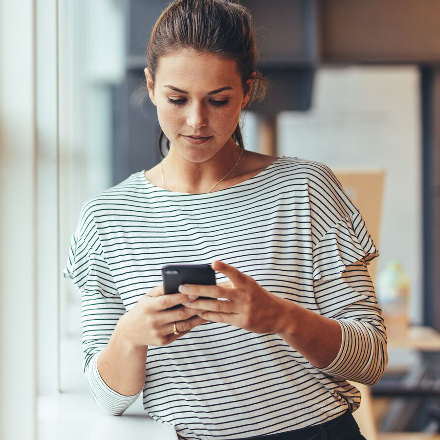 woman looking at smartphone in corridor 900x900